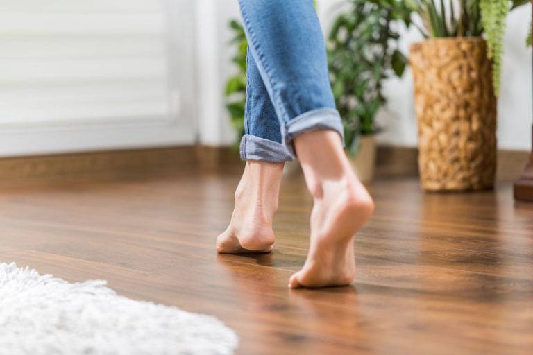 Woman's bare feet walking on wood floor