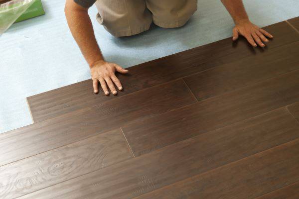 Man installing dark wood effect laminate flooring